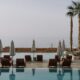 a pool with chairs and umbrellas by the water Marriott Bonvoy