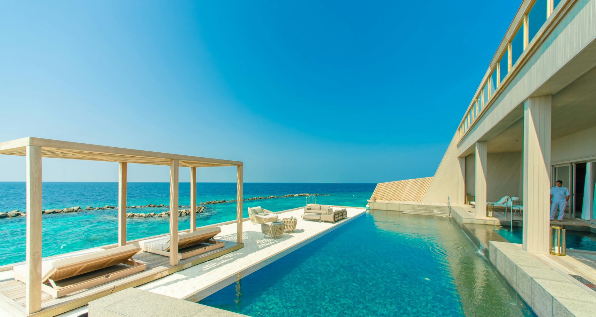 a swimming pool with lounge chairs and a deck on a beach