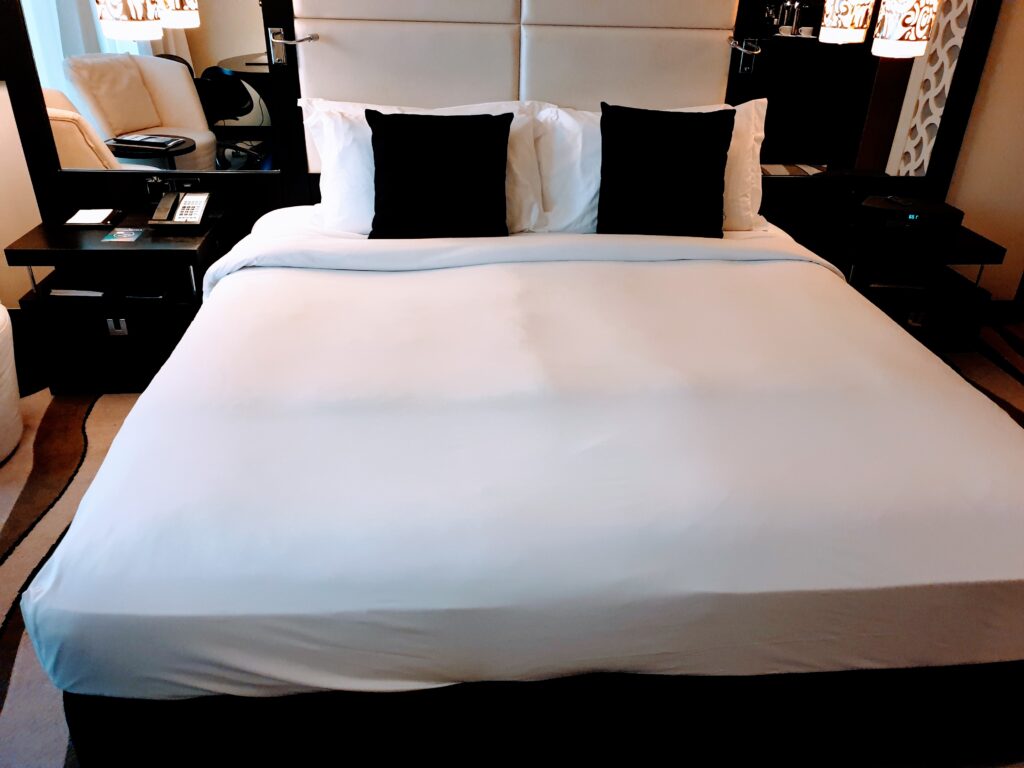 a bed with white sheets and black pillows Booking.com house scam 