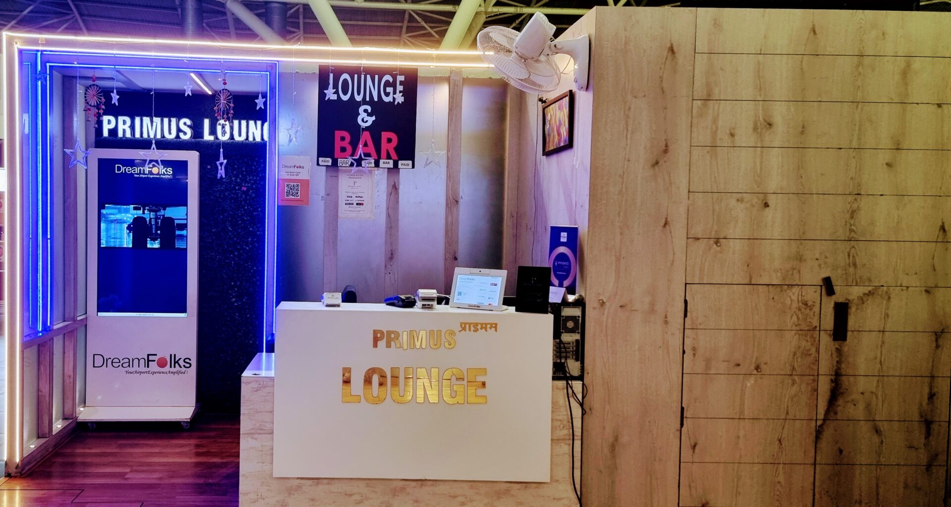 a white reception desk with a white hat and a sign Primus Lounge Amritsar