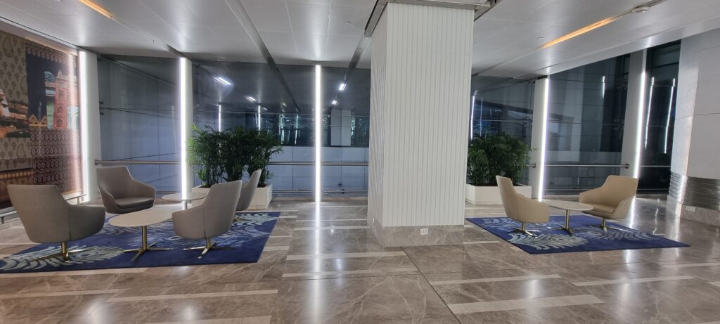 a large white column with chairs and plants in front of it entrance to Encalm Privé lounge Delhi