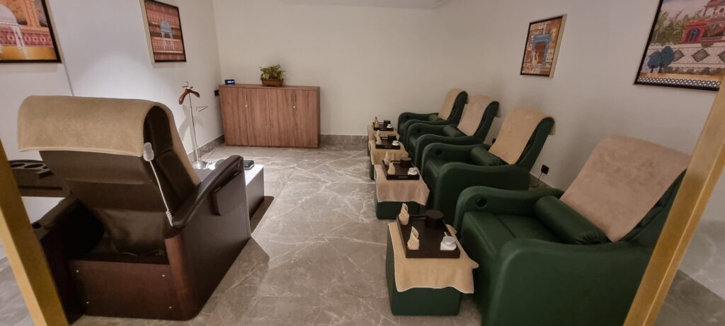 a room with green chairs and a table Encalm Privé lounge Delhi spa