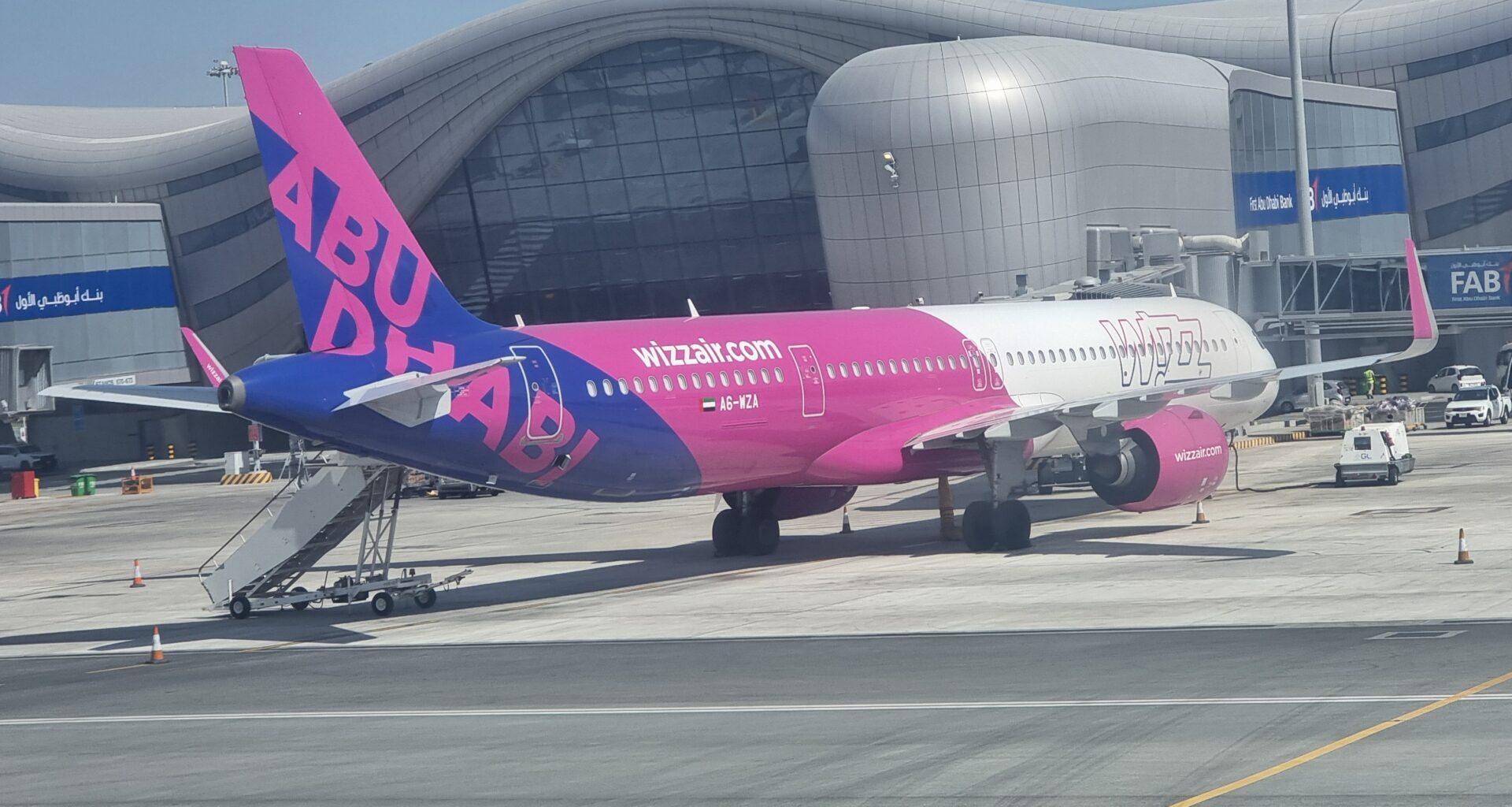 a pink and blue airplane in front of a building Wizz Air Israel
