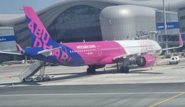 a pink and blue airplane in front of a building Wizz Air Israel