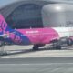 a pink and blue airplane in front of a building Wizz Air Israel