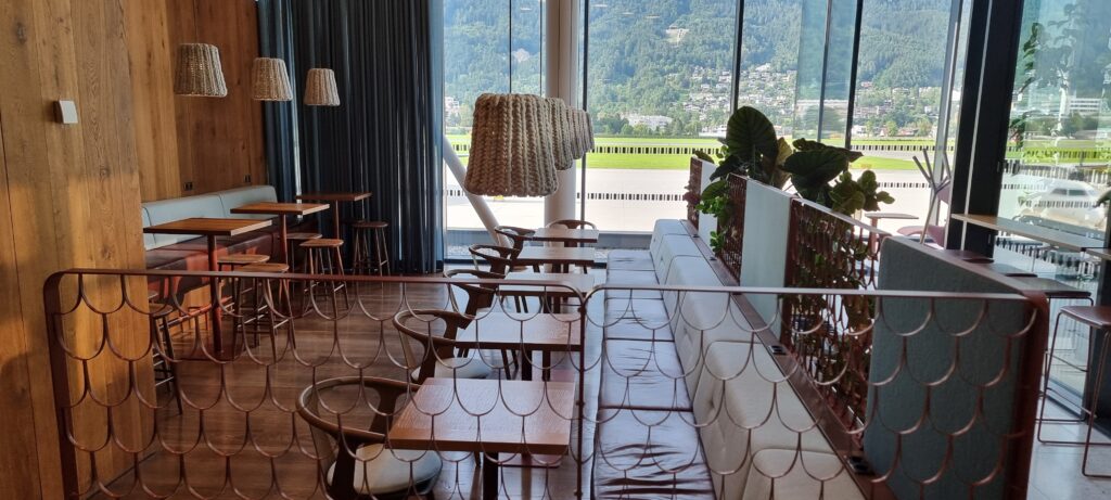 a room with tables and chairs and a large window Tyrol lounge