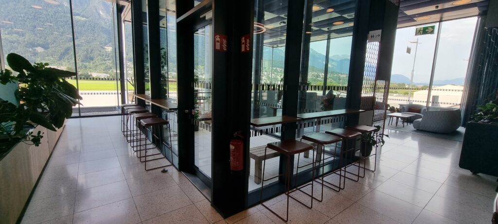 a row of stools in a room with glass walls Tyrol lounge Innsbruck airport