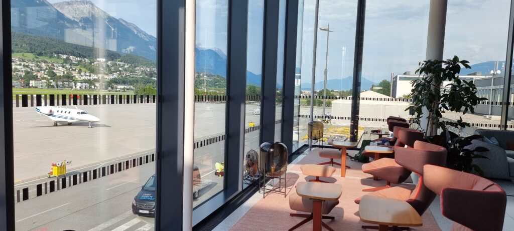 a room with a window and a view of the mountains and a road Tyrol lounge Innsbruck airport