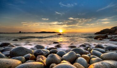 a rocky beach with water and a sunset virgin atlantic reward mastercard