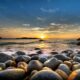 a rocky beach with water and a sunset virgin atlantic reward mastercard