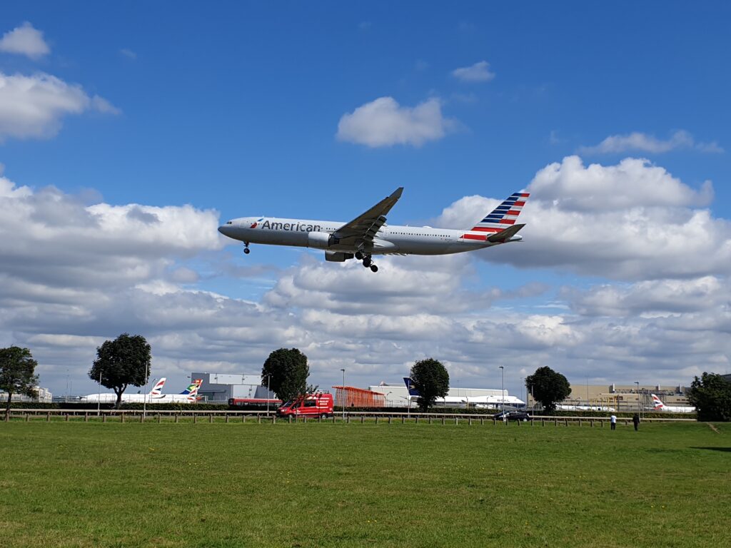 an airplane flying over a field American Airlines