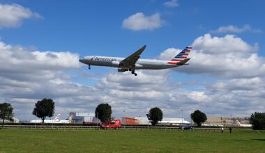 an airplane flying over a field American Airlines