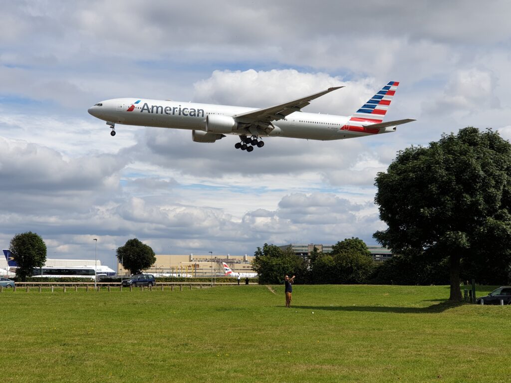 a plane flying over a field American Airlines