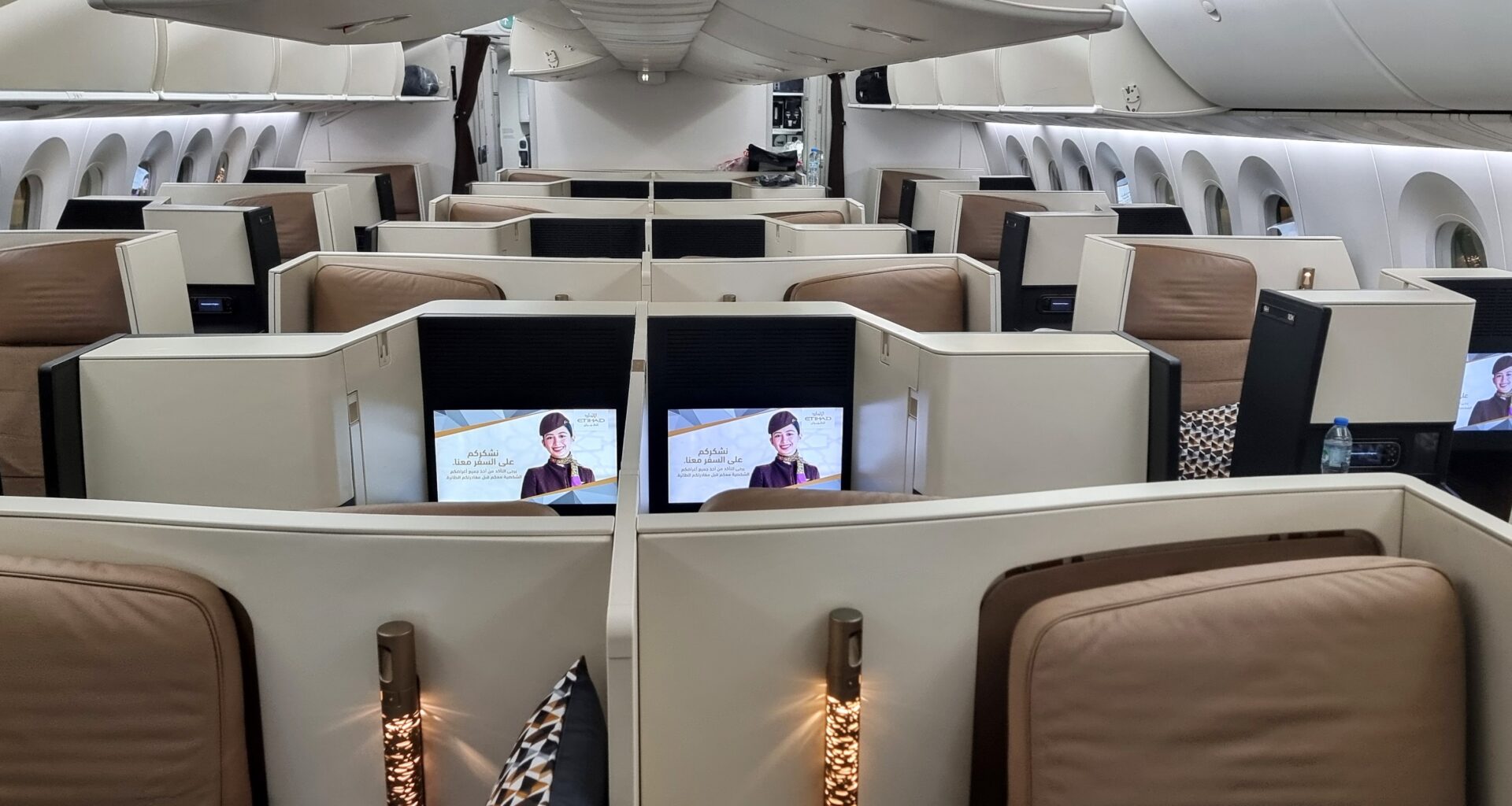 a row of chairs with monitors on the side booking tickets process airline Etihad