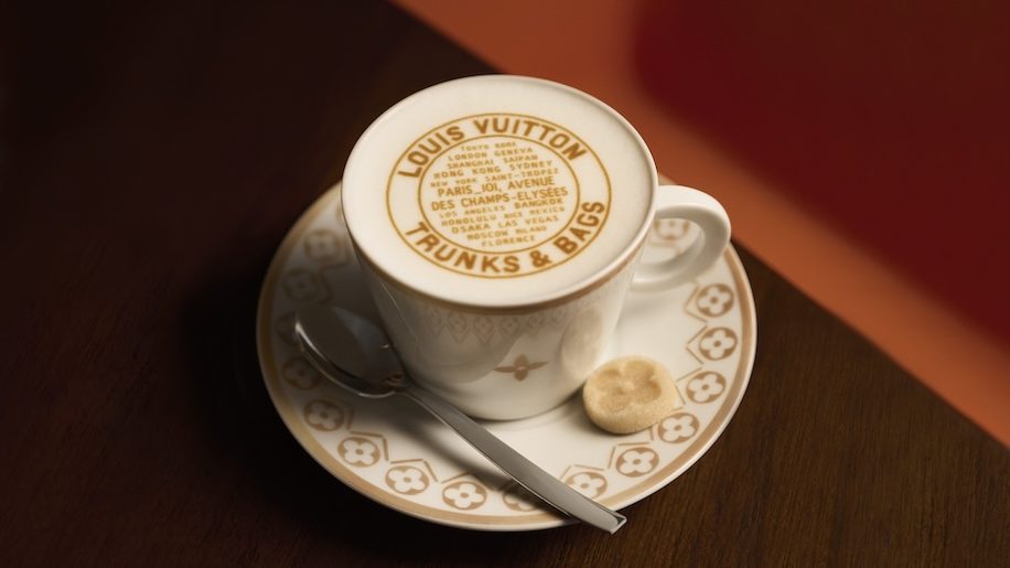 a cup of coffee with a spoon and a cookie Louis Vuitton cafe