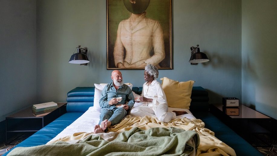 a man and woman sitting on a bed Small luxury Hotel