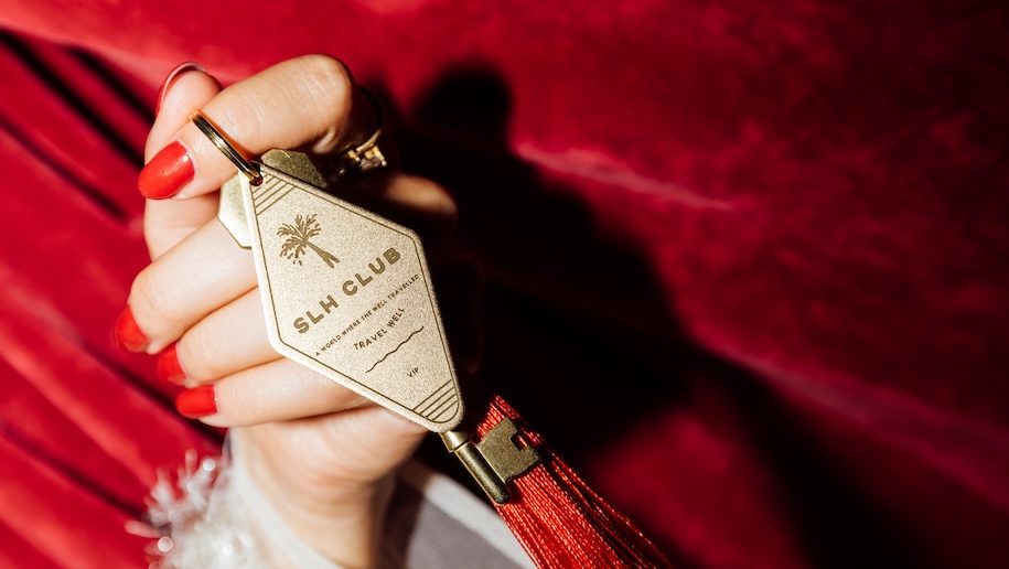 a person holding a key chain small luxury hotel