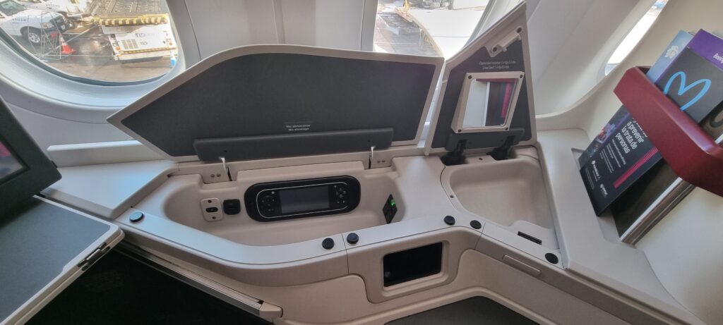 an airplane seat with a screen and a mirror Aeromexico business class