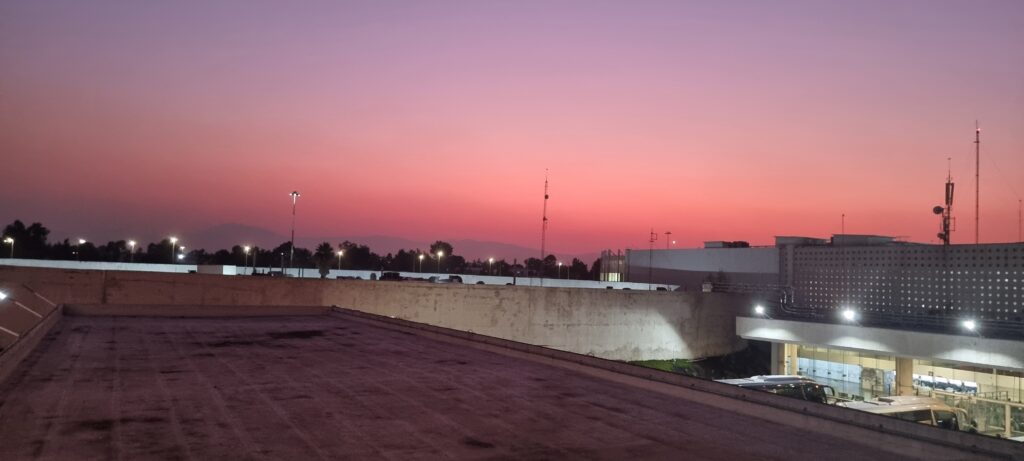 a rooftop of a building with a pink sky west east jetlag