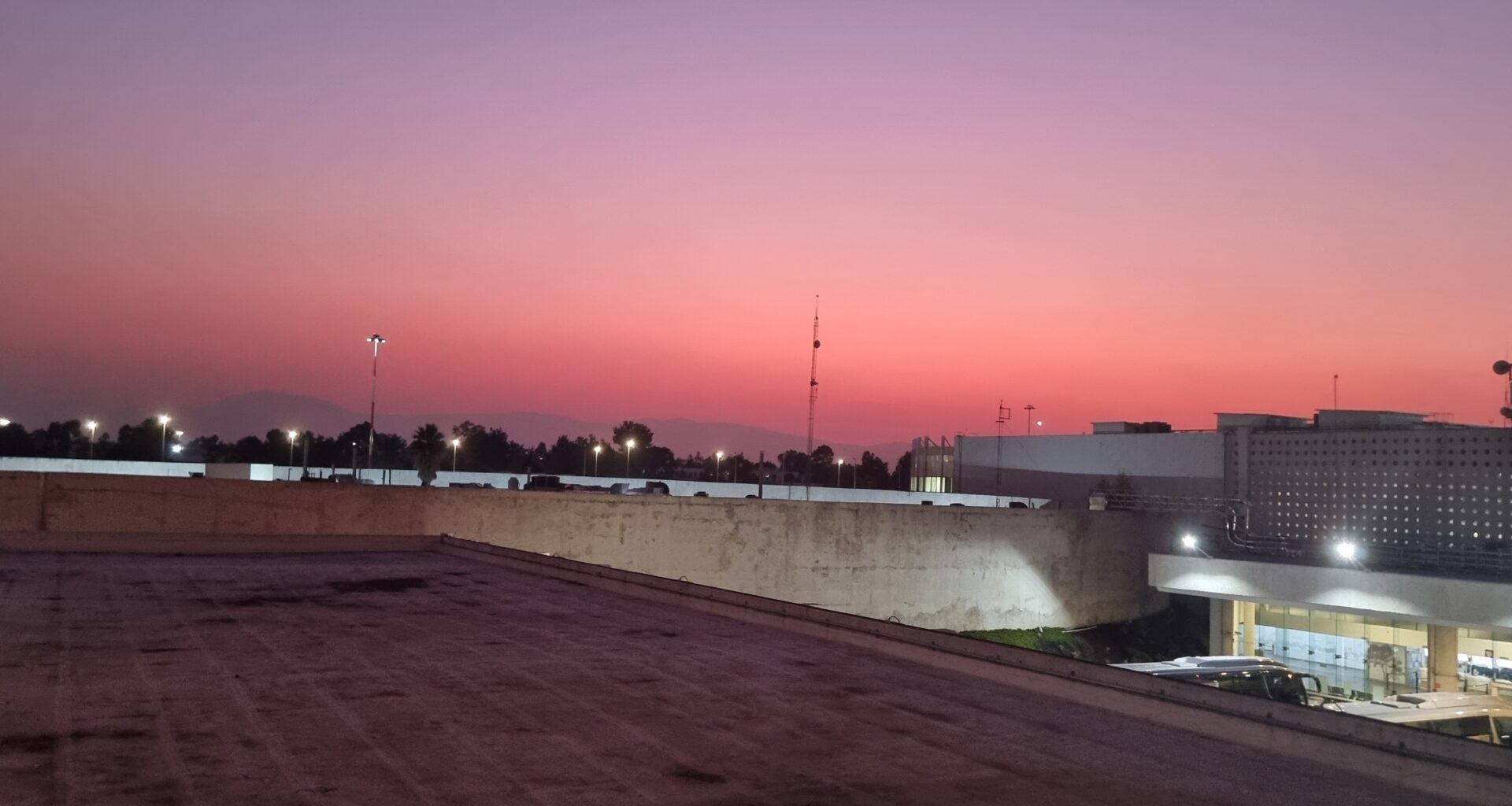 a rooftop of a building with a pink sky west east jetlag