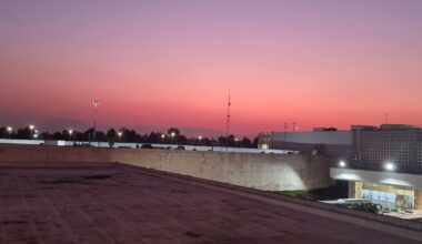 a rooftop of a building with a pink sky west east jetlag