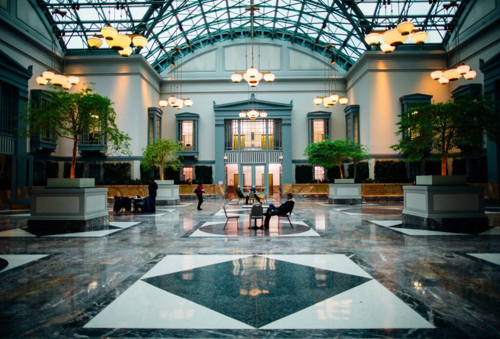 a large building with a glass roof and a large hall with people sitting on benches Hilton Honors