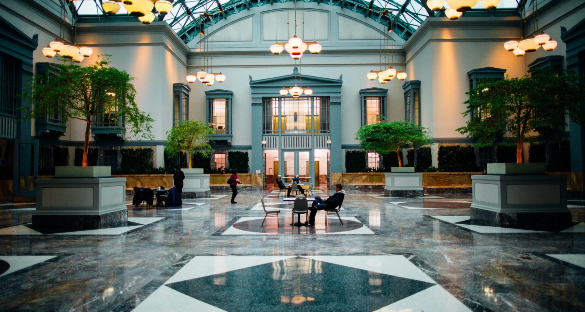 a large building with a glass roof and a large hall with people sitting on benches Hilton Honors