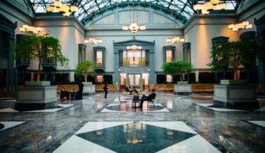 a large building with a glass roof and a large hall with people sitting on benches Hilton Honors