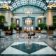 a large building with a glass roof and a large hall with people sitting on benches Hilton Honors