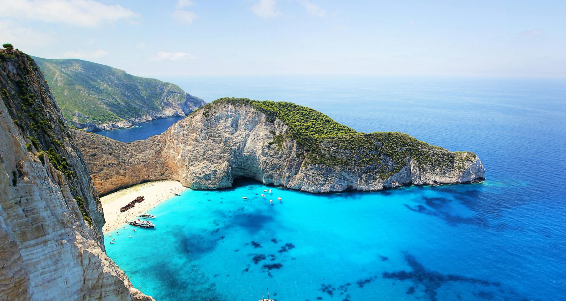 a beach with boats and blue water BA Freebird