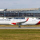 a large white and red airplane on a runway Qantas A321XLR