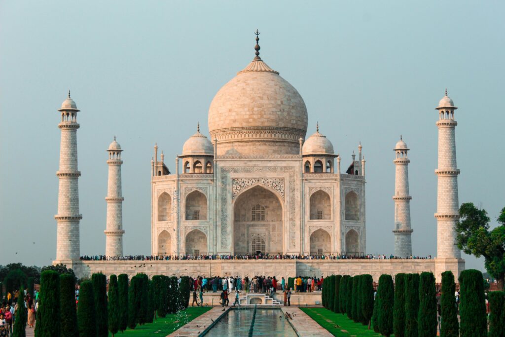 a large white building with a dome and a pool of water with Taj Mahal in the background BA freebird