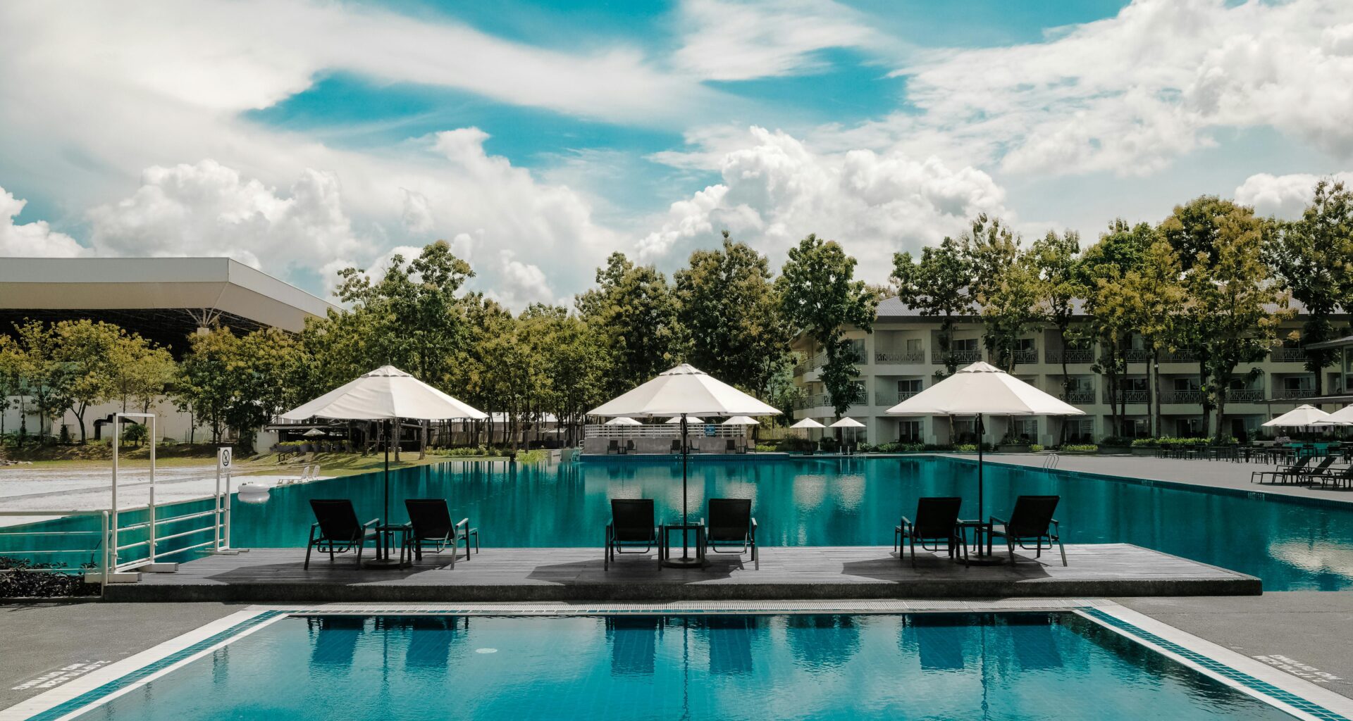 a pool with chairs and umbrellas Hilton Honors Plus Debit Card