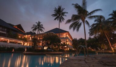 a pool with palm trees and buildings in the background Hilton Honors Debit Card