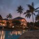 a pool with palm trees and buildings in the background Hilton Honors Debit Card