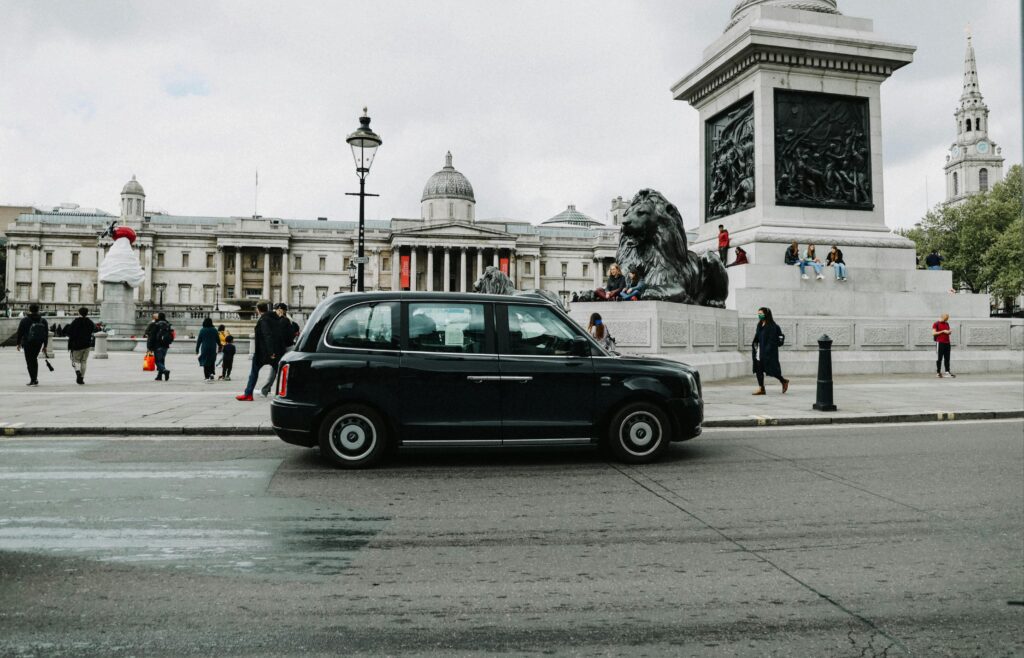 a black car on a street with a statue in front of it