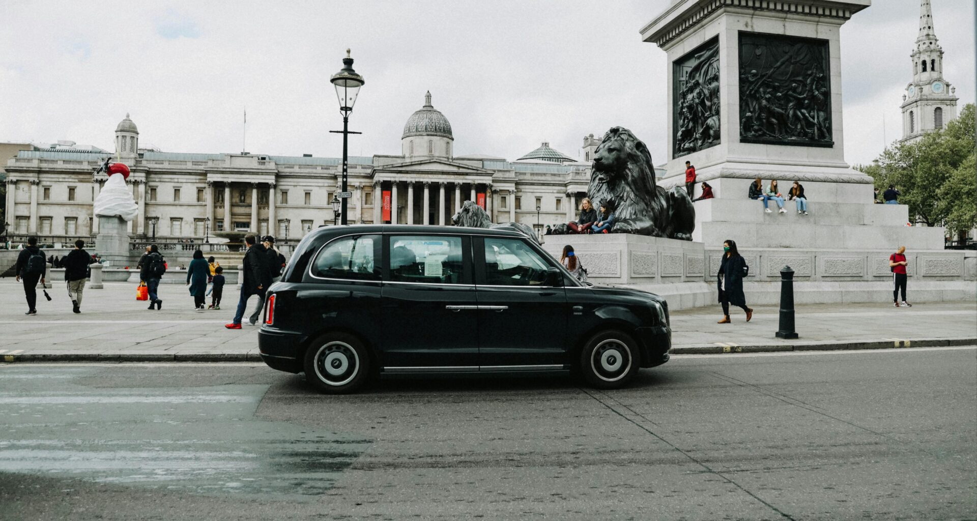 a black car on a street with a statue in front of it