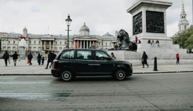 a black car on a street with a statue in front of it