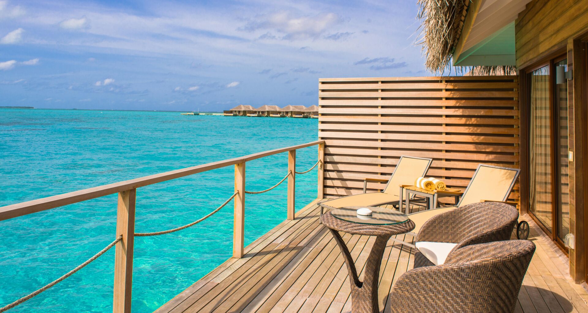 a deck with chairs and a table overlooking the ocean British Airways VS Virgin Atlantic