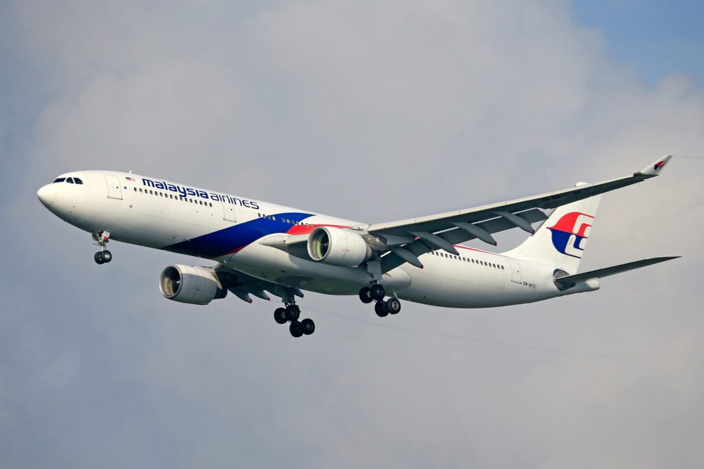 a large airplane flying in the sky Malaysia airlines