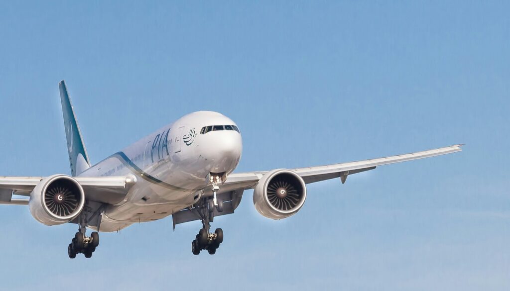a white airplane flying in the sky PIA UK flights
