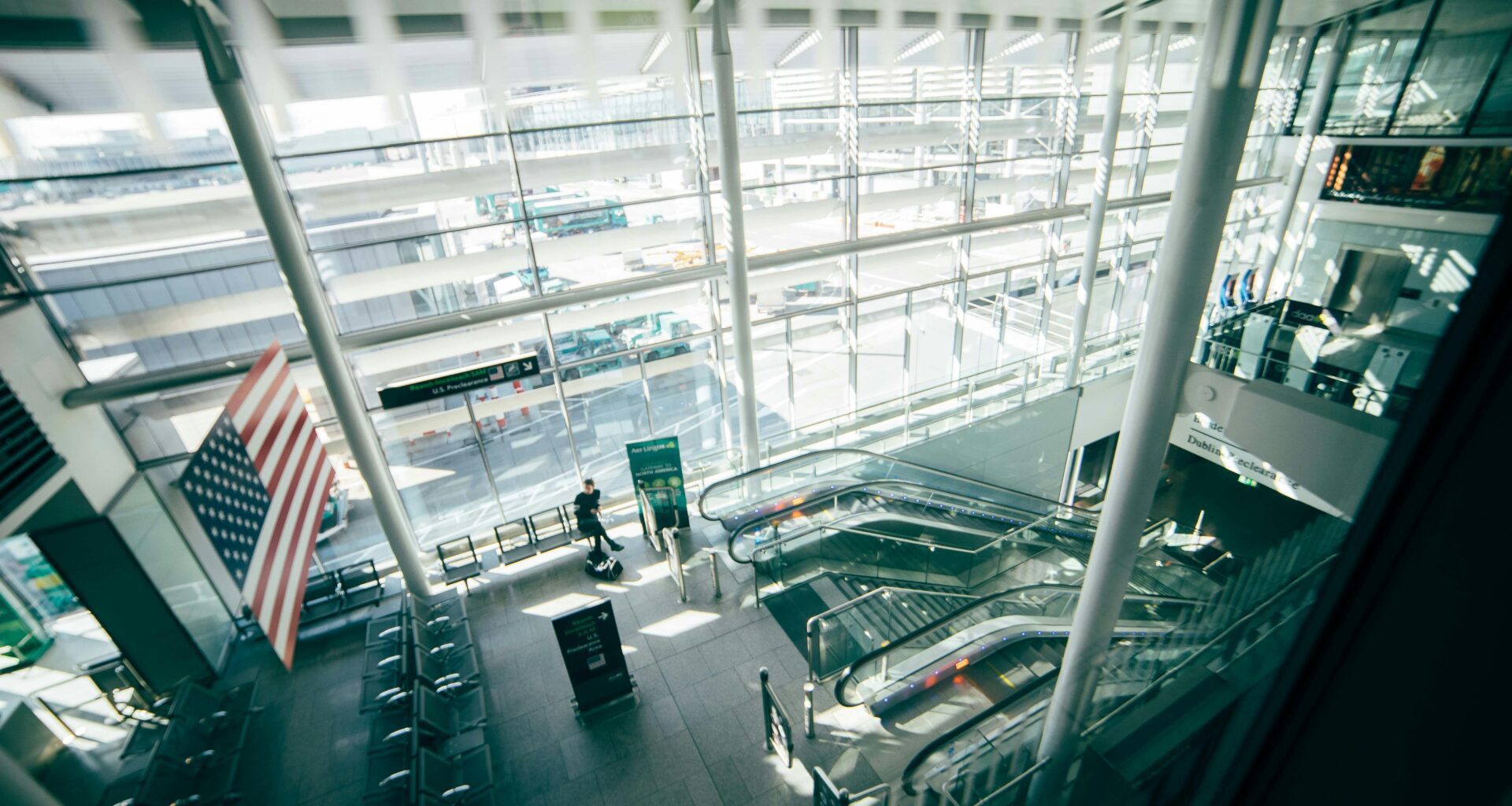 a man standing in a building with escalators Dublin Airport Preclearance