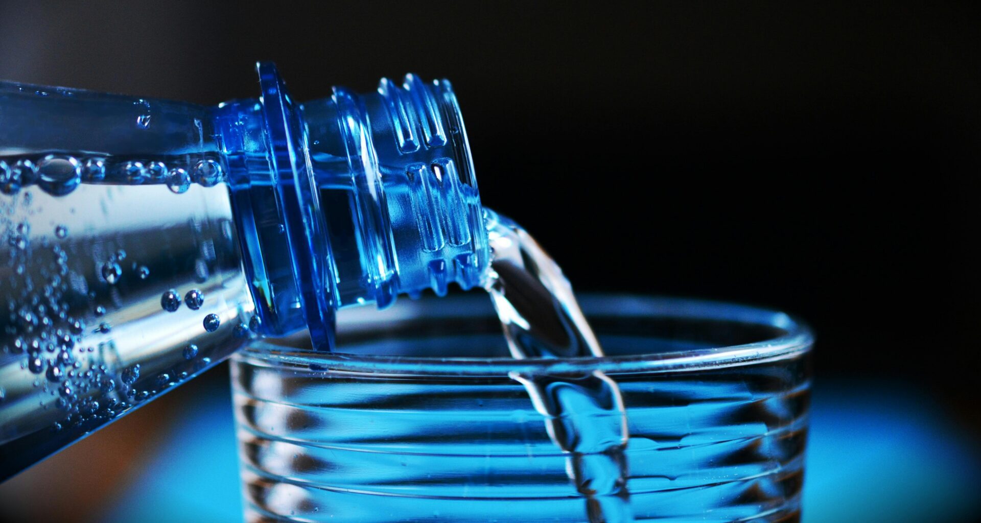 a close up of a bottle pouring water into a glass British Airways bottled water