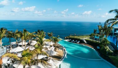 a pool with palm trees and a beach and a body of water