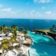 a pool with palm trees and a beach and a body of water