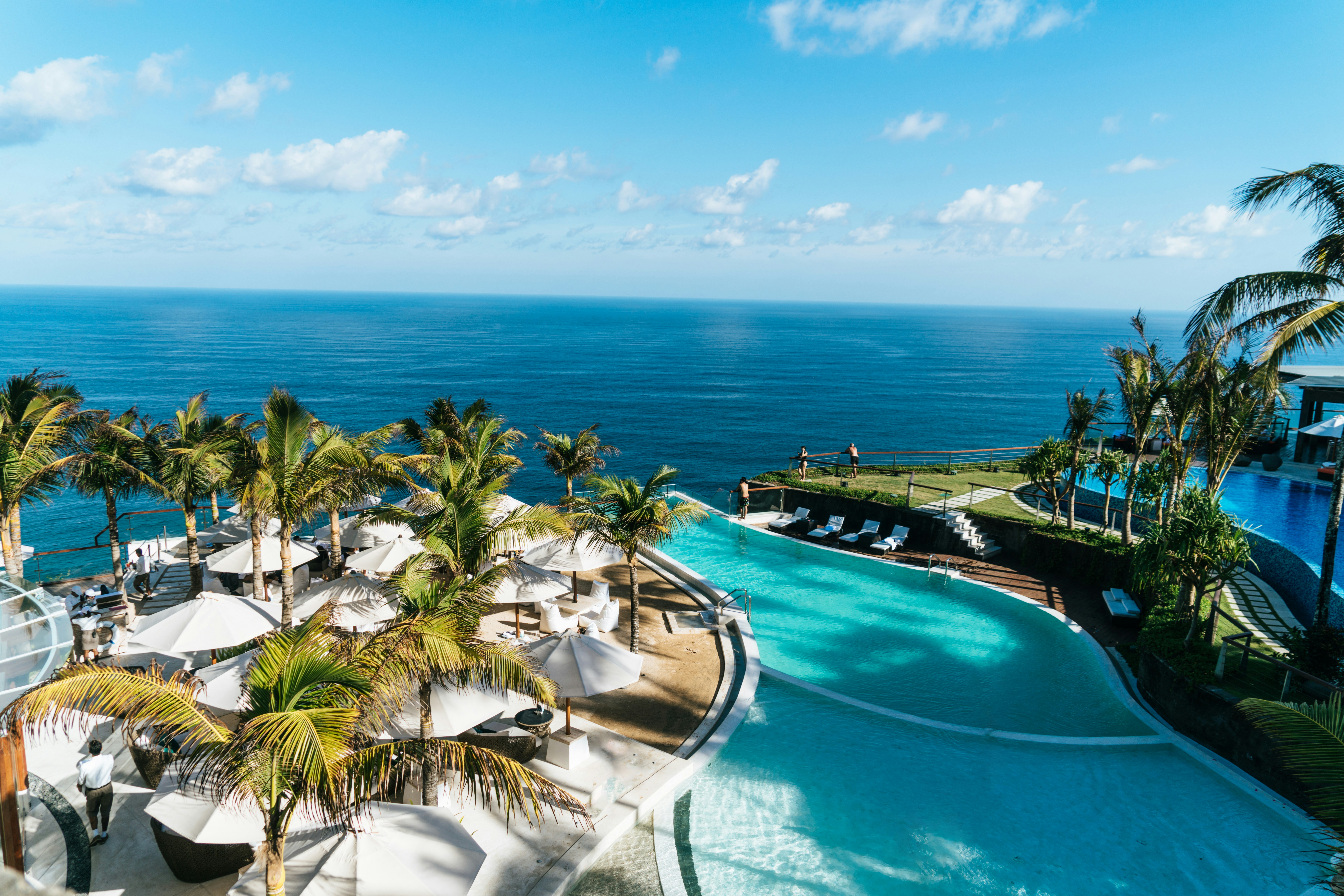 a pool with palm trees and a beach and a body of water