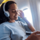 a woman wearing headphones and smiling Priority pass TrvlWell
