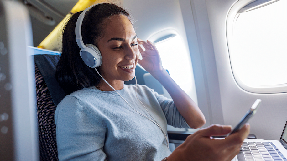 a woman wearing headphones and smiling Priority pass TrvlWell