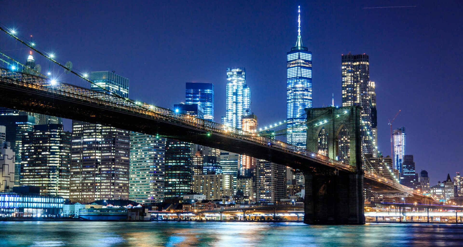 a bridge over water with city skyline at night Virgin Hotels New York