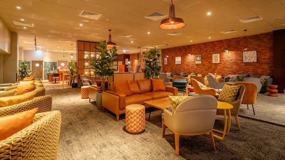 a room with furniture and a brick wall No1 Lounge Heathrow T3